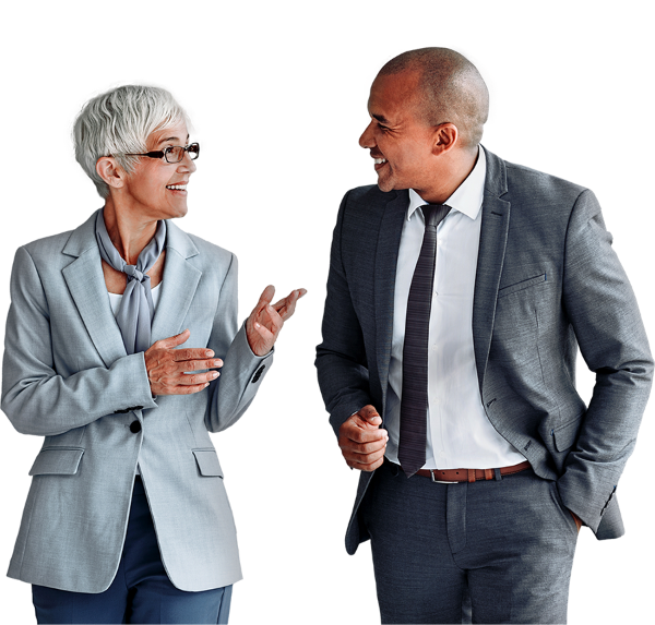 Two people dressed in business attire are standing together. One is wearing a light blazer and dark pants, and the other is wearing a dark suit with a tie. They appear to be engaged in conversation.