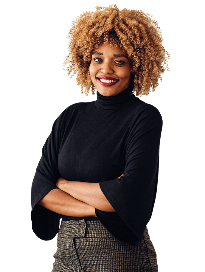 A person with curly hair is wearing a long-sleeve top and checkered pants, with arms crossed.